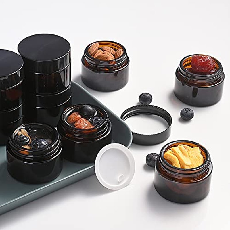Bumobum 1 oz Amber Glass Jars with Lids, 105 pack Clear Small Jars with Black Lids, White Labels and Inner Liners, Empty Round Cosmetic Containers for Cream, Lotion (Amber 105 Pack)